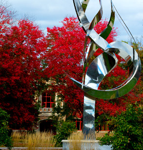Flame of the Millennium sculpture on 缅北视频 campus with fall foliage and Moench Hall in background.