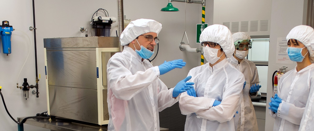 People in clean room attire work together in the MiNDS lab. 