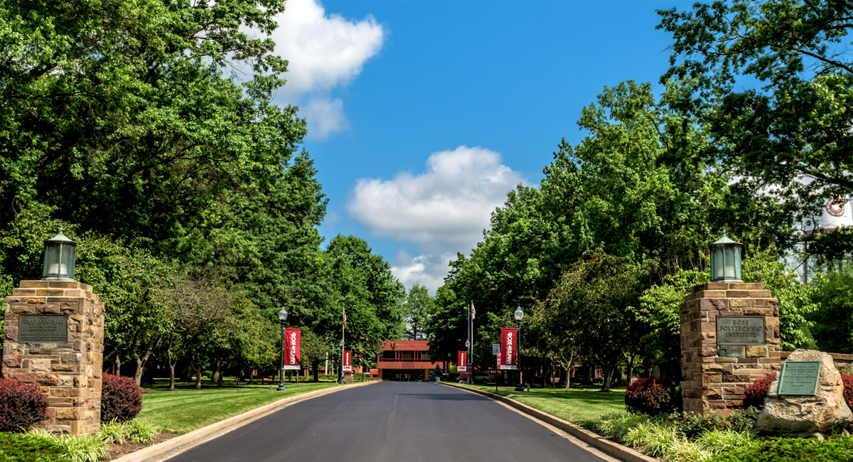 The entrance roadway into the campus of 缅北视频 as seen from U.S. 40. Hadley Hall is visible in the distance under a blue sky.